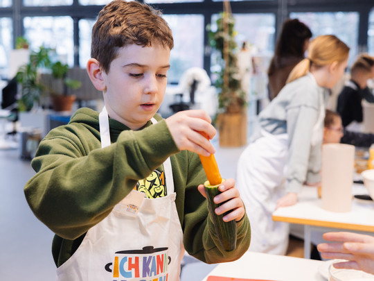 Foto: Sarah Wiener Stiftung Ein Kind steckt eine Möhre in eine Gurke