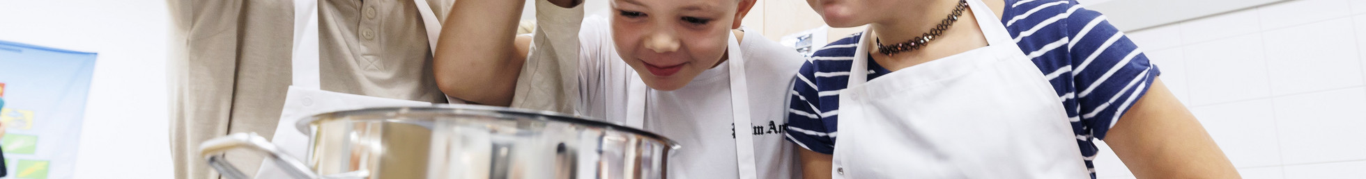 Drei Kinder gucken in einen Kochtopf