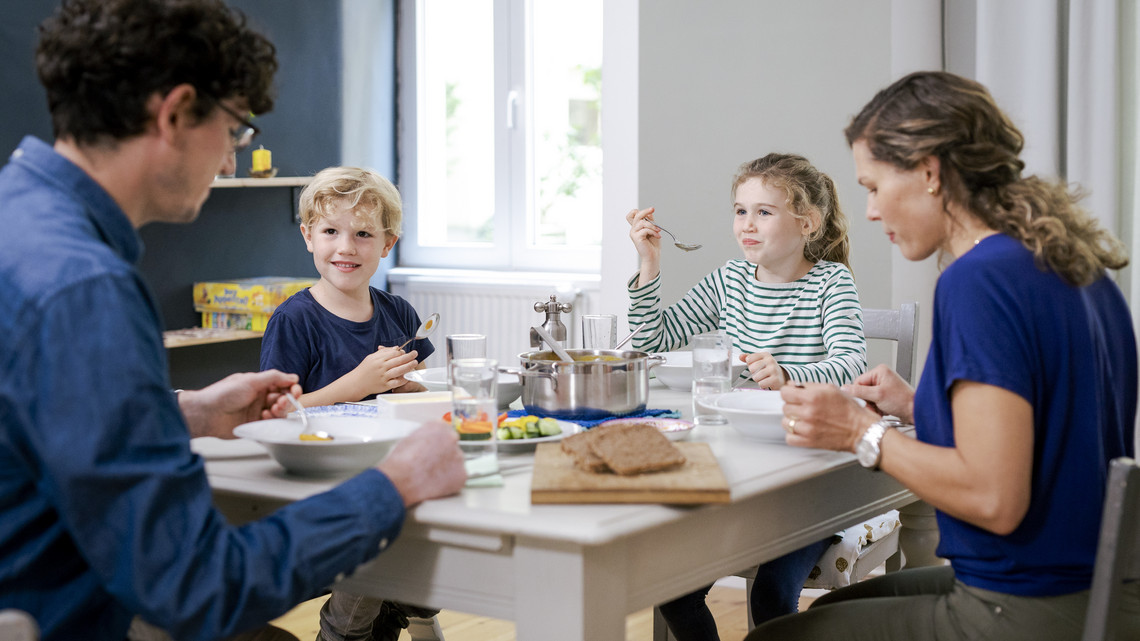 Foto: Sarah Wiener Stiftung | photothek Zwei Erwachsene und zwei Kinder essen am Esstisch