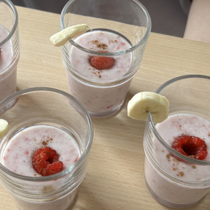 Vier Gläser mit rosafarbenem Fruchtsmoothie
