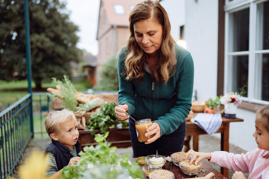 Foto: Hubertus Huverman Sarah Wiener mit Apfelmus und zwei Kindern
